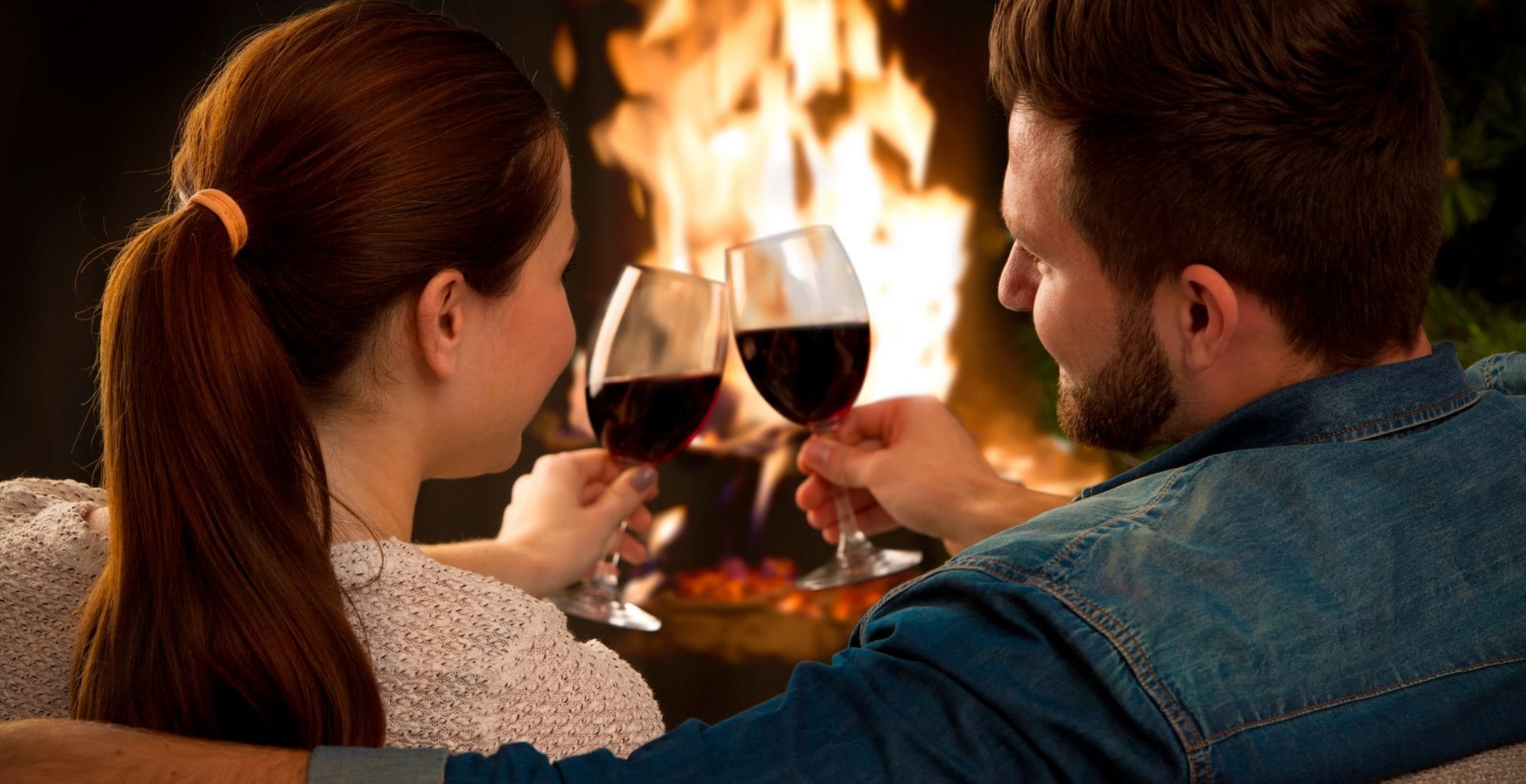 Couple with glass of wine at fireplace
